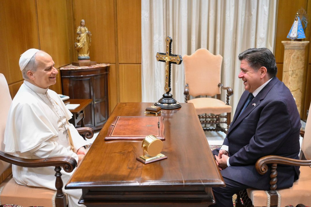 Pritzker and the pope sitting at a desk