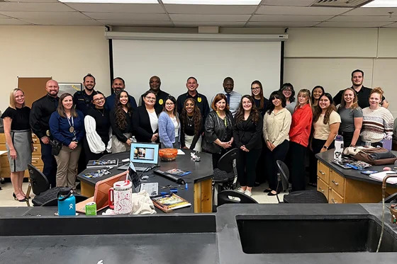 A group of students stand in front of a projector screen