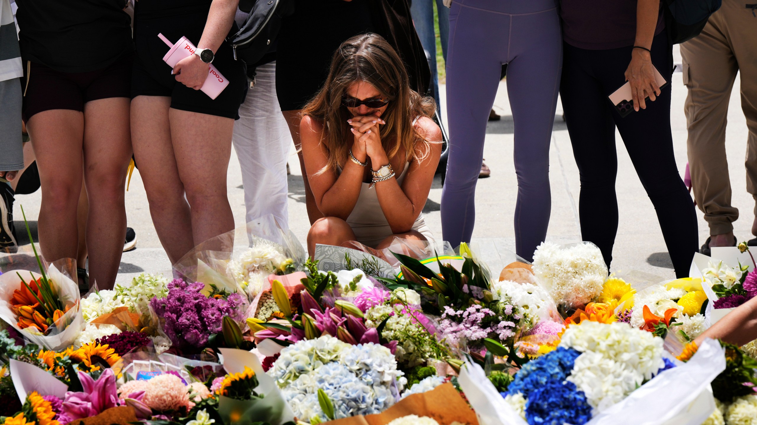 A woman kneels and prays at a flower memorial to shooting victims outside the Bondi Pavilion at Sydney's Bondi Beach, Monday, Dec. 15, 2025, a day after a shooting. (AP Photo/Mark Baker)