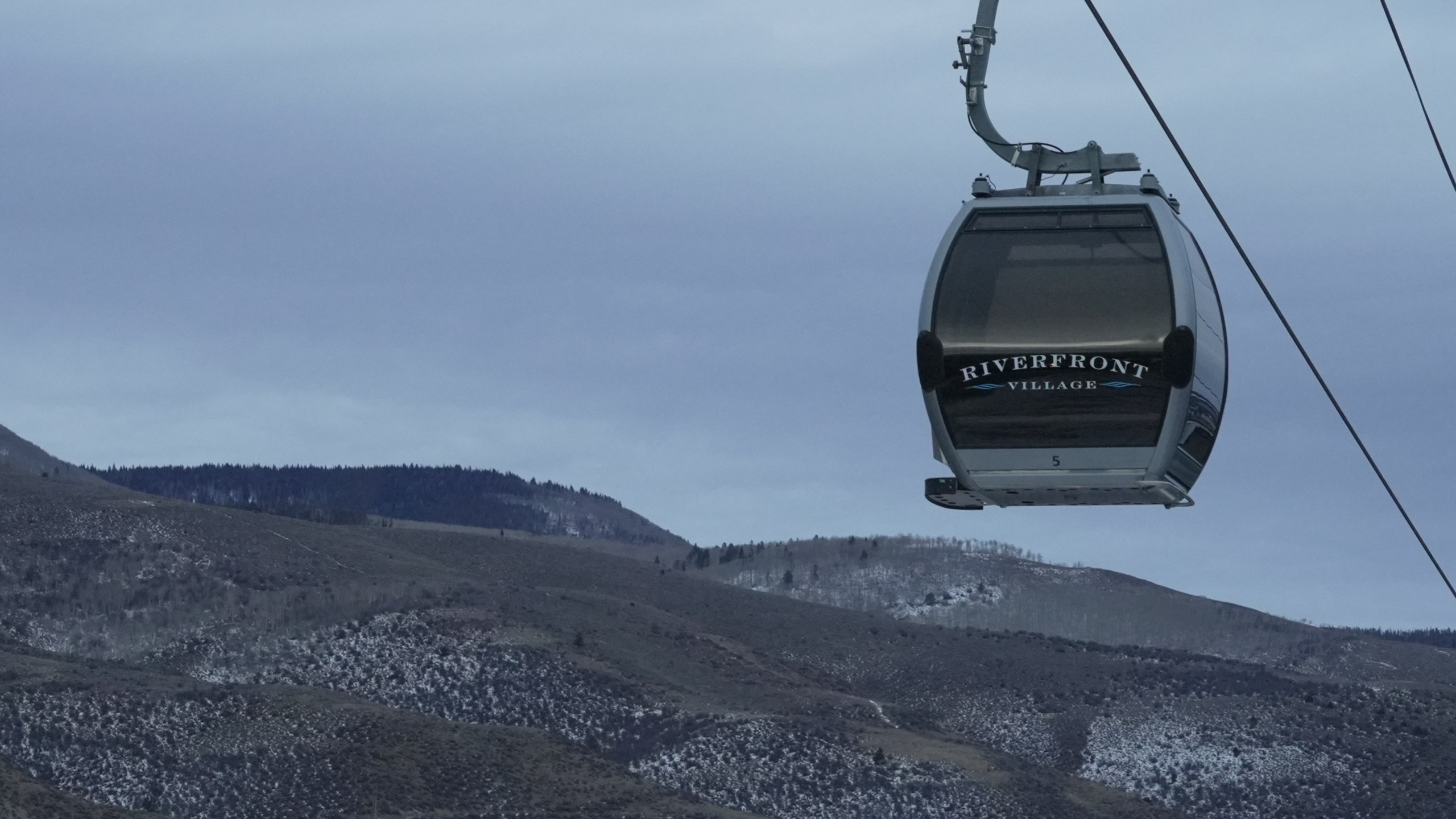 A gondola hangs in front of snow-scarce mountains Thursday, Dec. 18, 2025, in Avon, Colo. (AP Photo/Brittany Peterson)