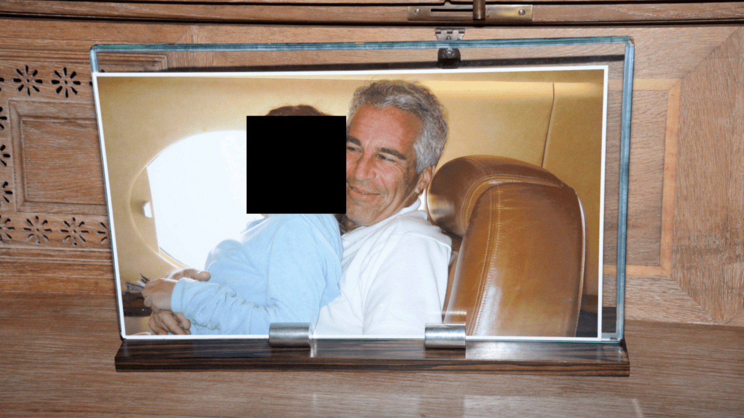 This redacted photo released by the U.S. Department of Justice shows a framed photograph of Jeffrey Epstein with a person on his lap, documented on Aug. 12, 2019, during a search of his home on Little St. James island in the U.S. Virgin Islands. (U.S. Department of Justice via AP)