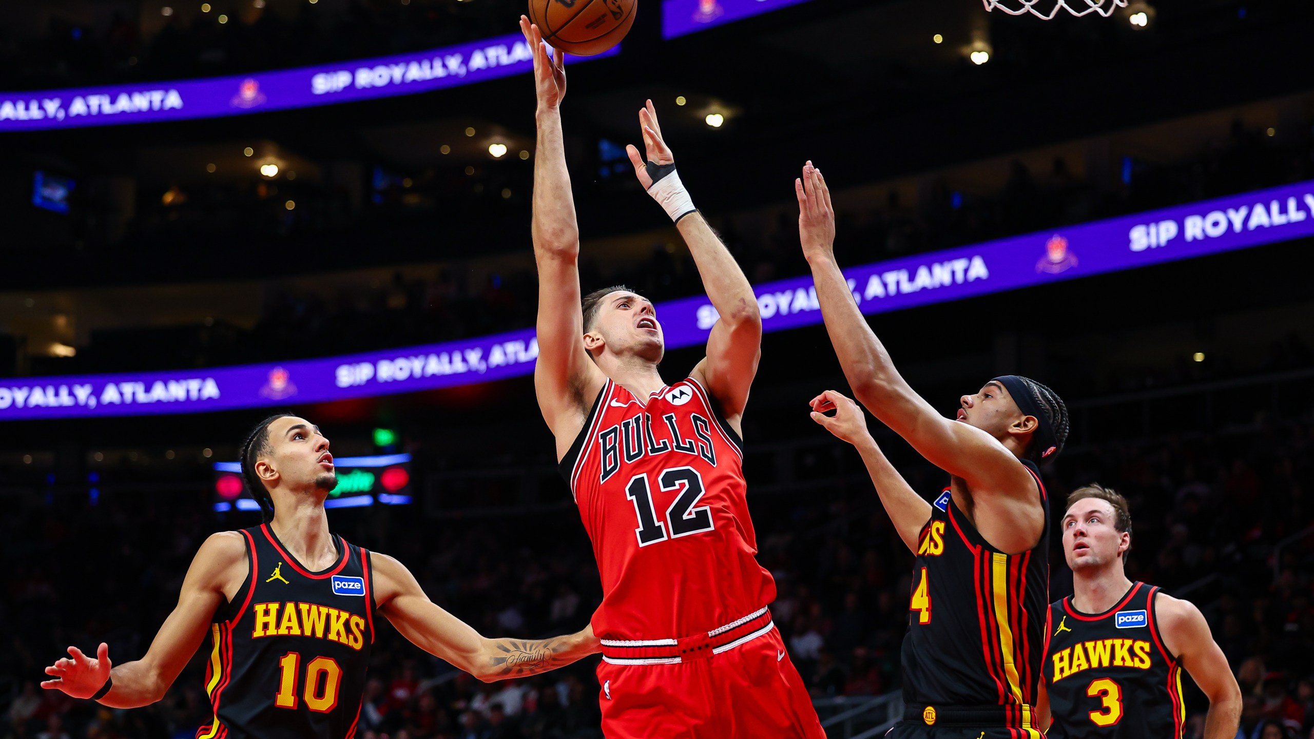 Chicago Bulls forward Zach Collins (12) shoots over Atlanta Hawks forward Asa Newell, right, during the first half of an NBA basketball game, Sunday, Dec. 21, 2025, in Atlanta. (AP Photo/Colin Hubbard)