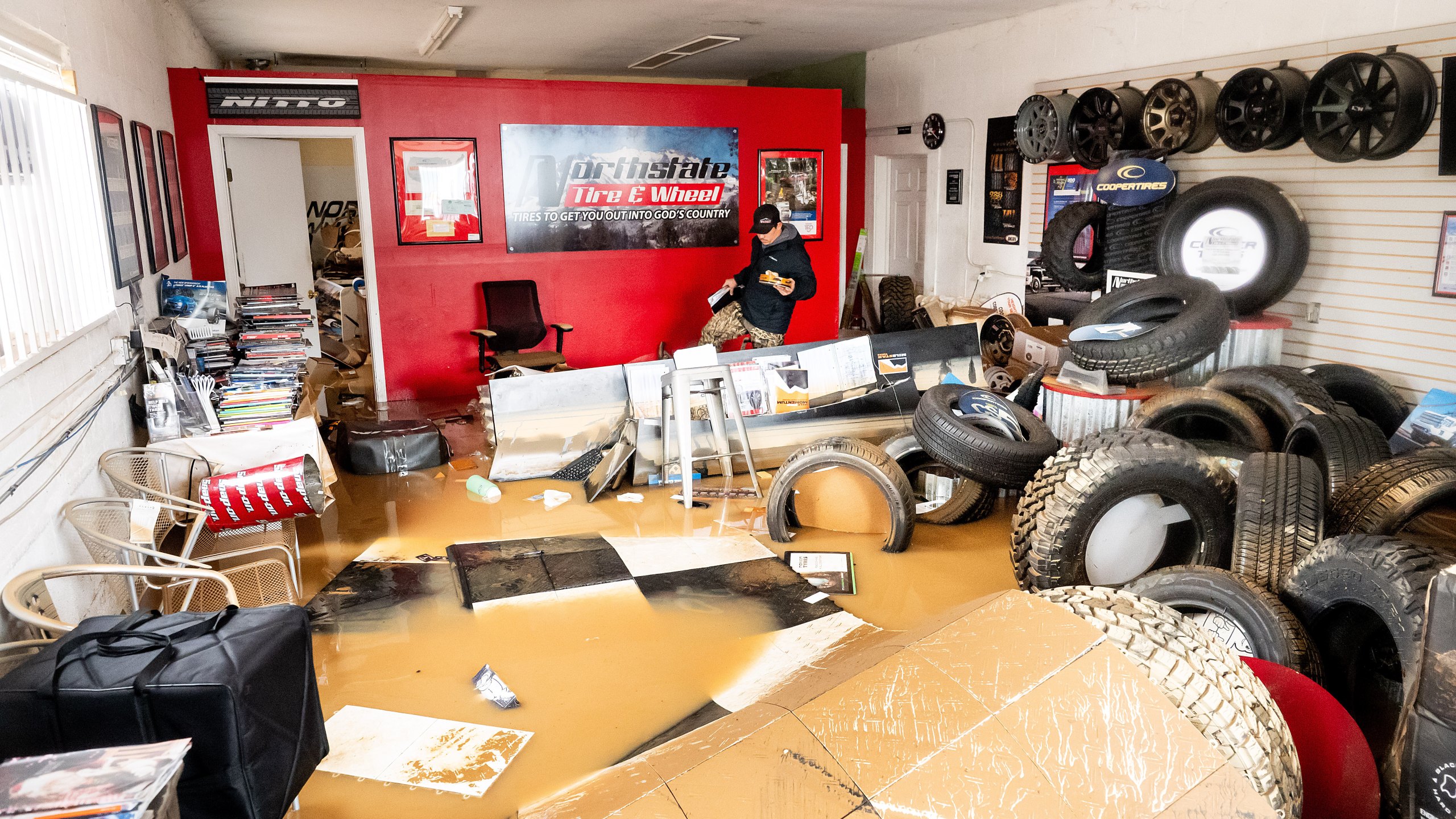 Dekoda Cruz walks through the flooded office of Northstate Tire & Wheel following heavy rains on Monday, Dec. 22, 2025, in Redding, Calif. (AP Photo/Noah Berger)