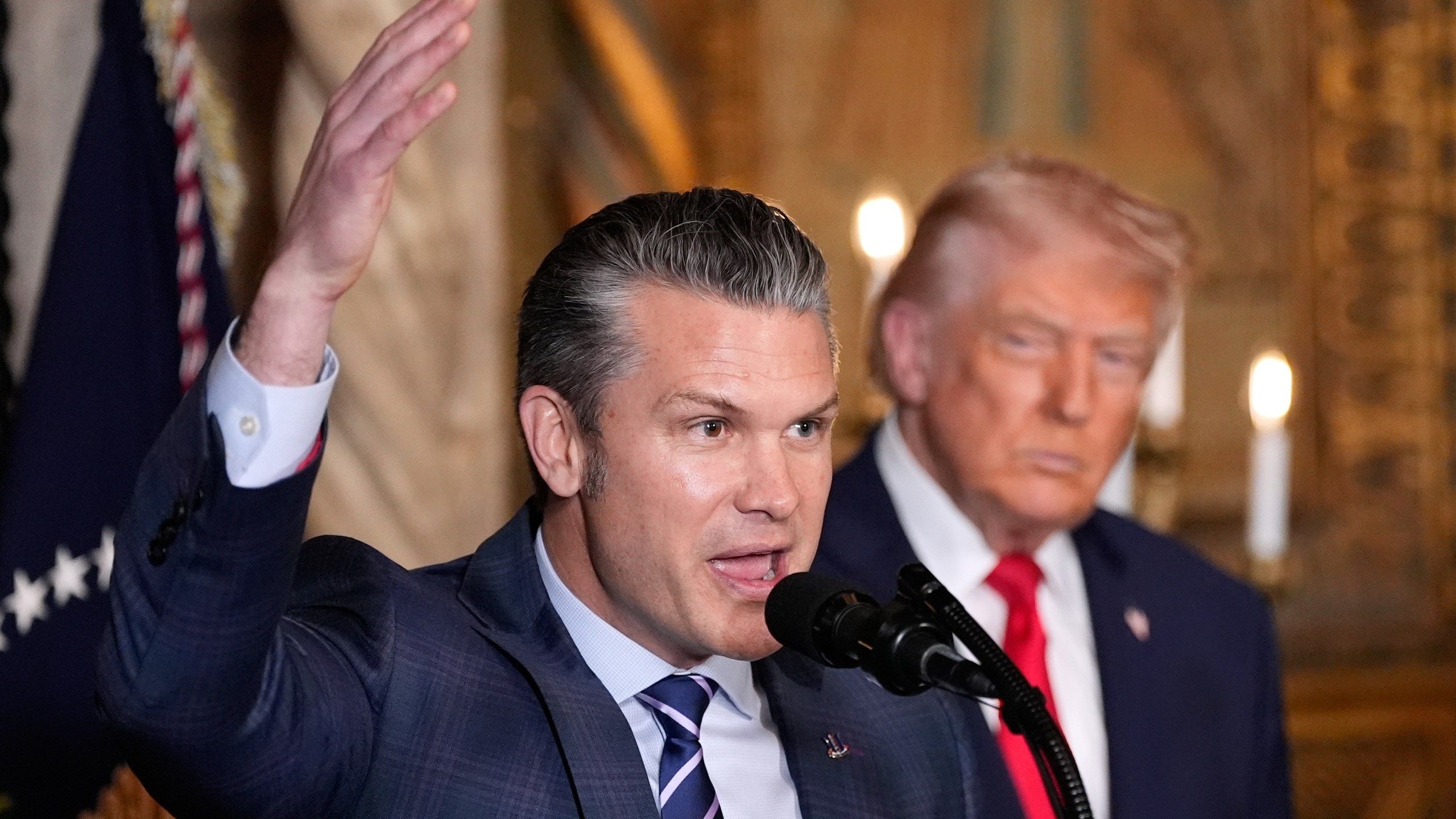 Defense Secretary Pete Hegseth speaks as President Donald Trump looks on, at Trump's Mar-a-Lago club, Monday, Dec. 22, 2025, in Palm Beach, Fla. (AP Photo/Alex Brandon)