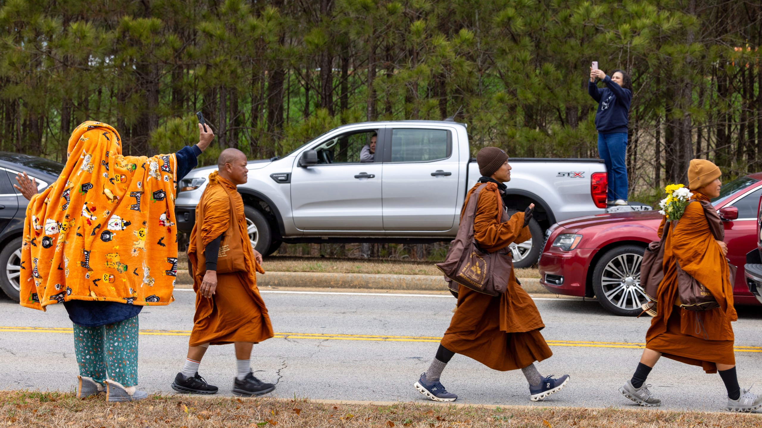 Supporters watch Buddhist monks on a "Walk for Peace" on Veterans Parkway in Fayetteville, Ga., on Monday, Dec. 29, 2025, from Texas to Washington, D.C. (Arvin Temkar/Atlanta Journal-Constitution via AP)