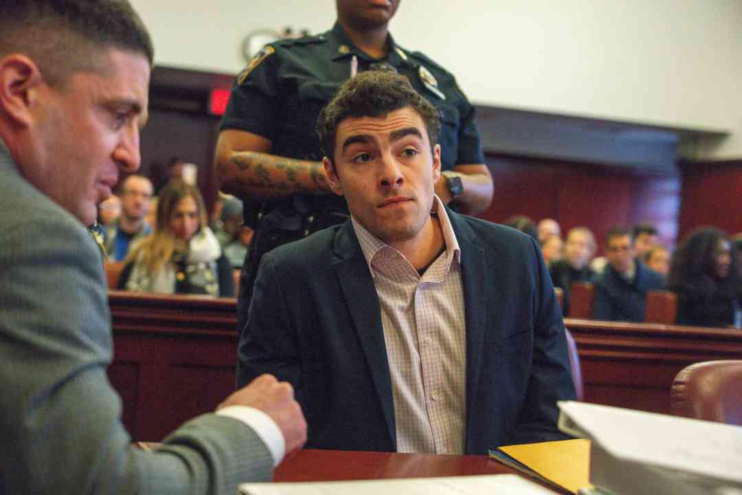 Luigi Mangione in a court room wearing a dak gray blazer and tan shirt