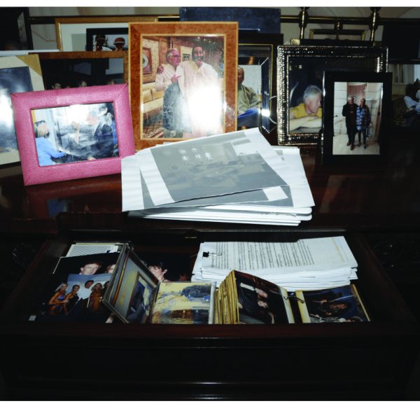 Picture of Jeffrey Epstein case files, showing piles of photos with various people.