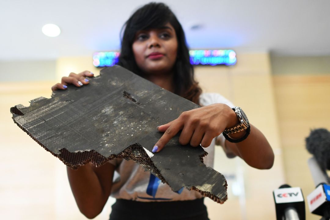 Woman holds a piece of debris believed to be from flight MH370