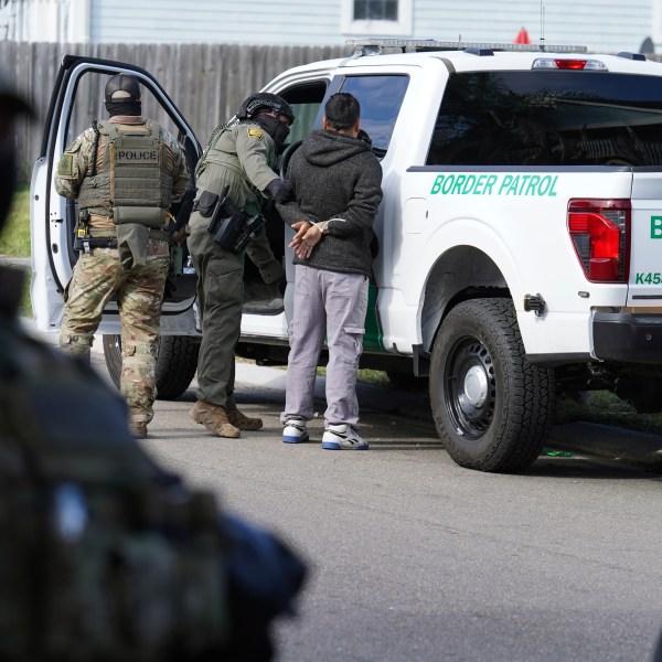 a man being detained by Border Patrol agents near a truck