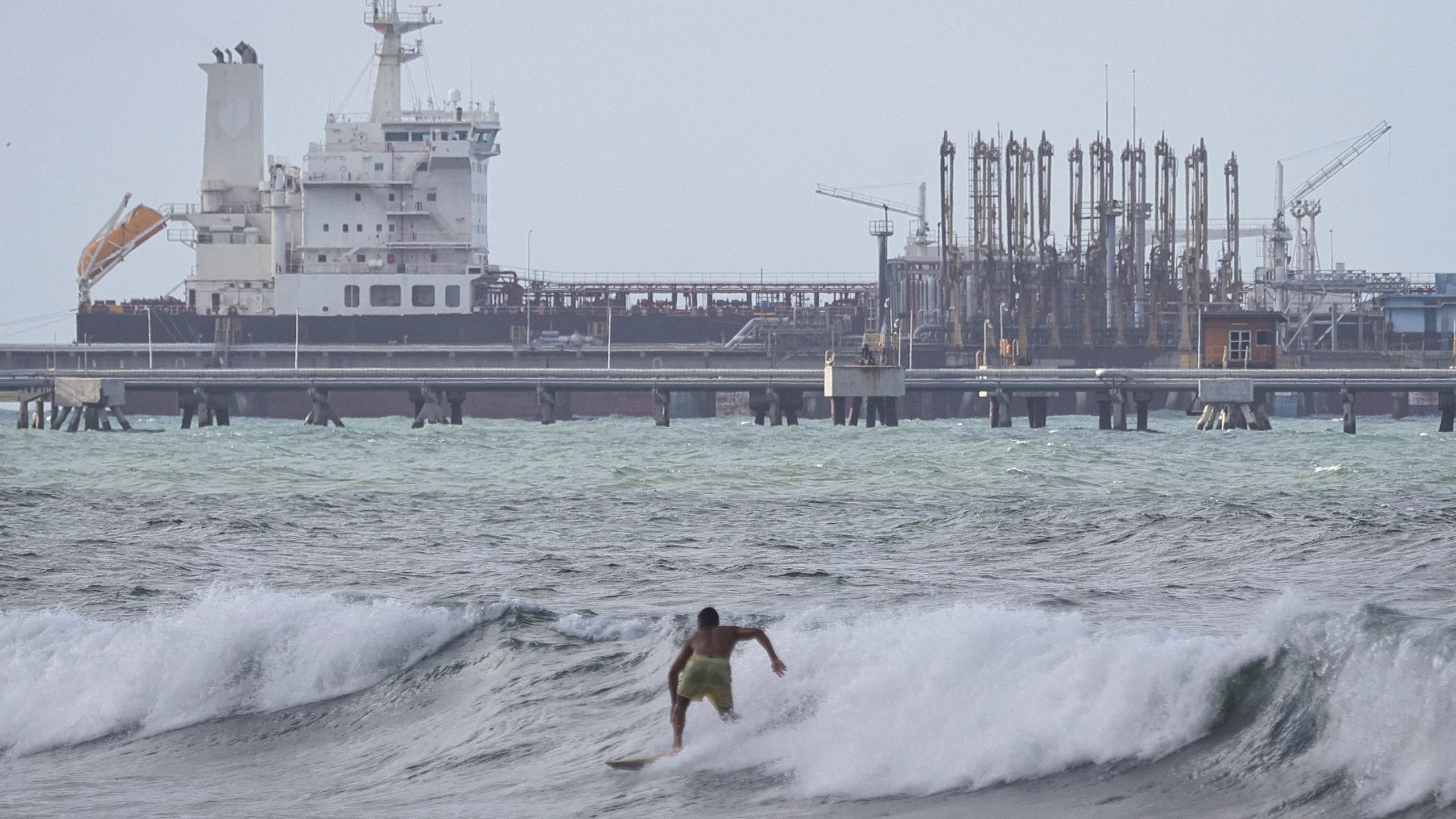 oil refinery along Venezuela coast, surfers in foreground