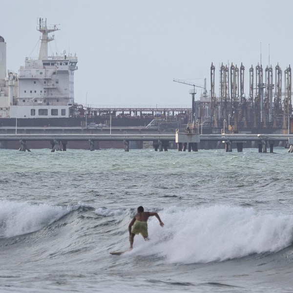 oil refinery along Venezuela coast, surfers in foreground