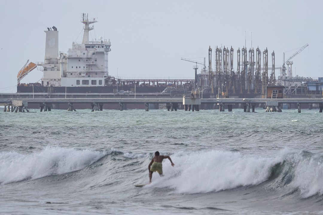 oil refinery along Venezuela coast, surfers in foreground