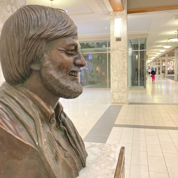 Bronze George Romero bust in foreground, mall corridor in background