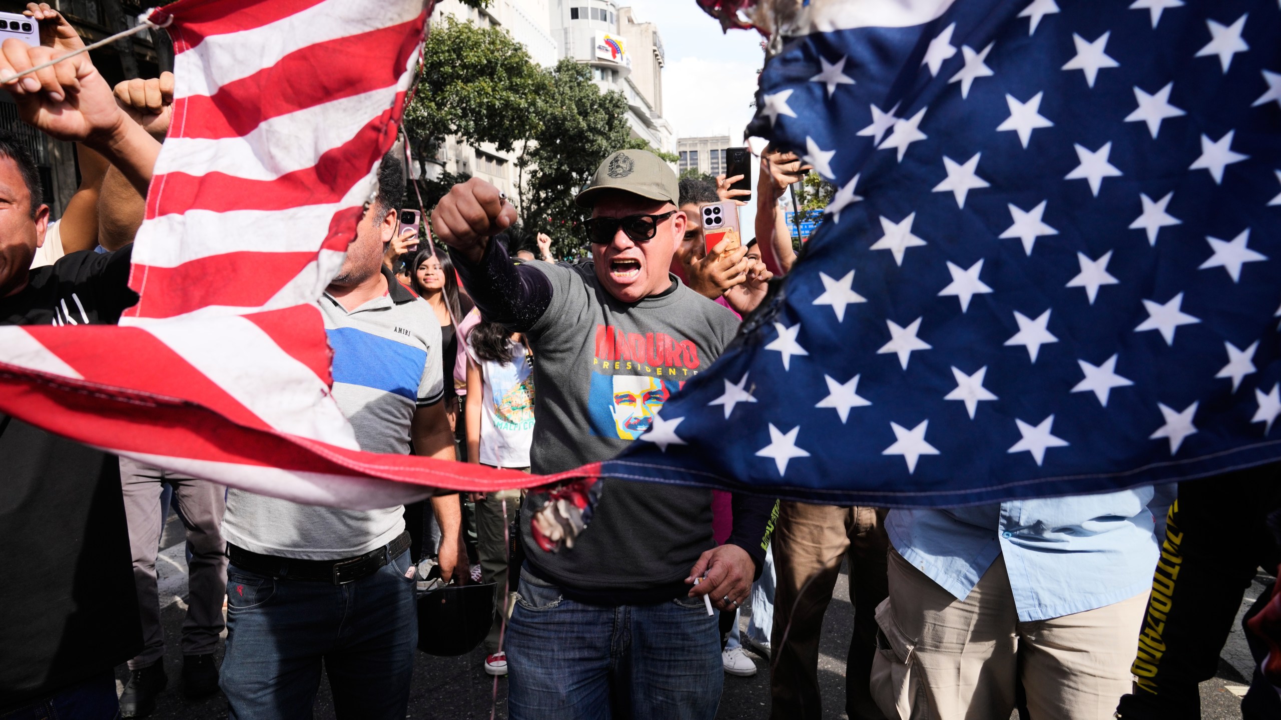 Government supporters rip an American flag in half during a protest in Caracas, Venezuela, Saturday, Jan. 3, 2026, after U.S. President Donald Trump announced that U.S. forces had captured President Nicolás Maduro and first lady Cilia Flores. (AP Photo/Ariana Cubillos)