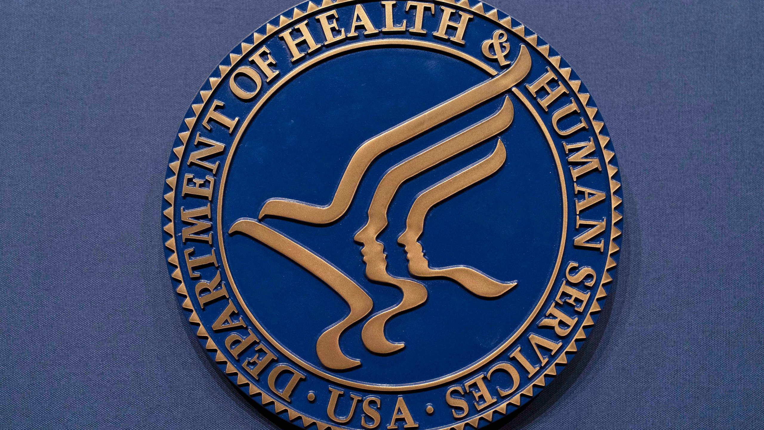 FILE = The Health and Human Services seal is seen before the news conference of Secretary Robert F. Kennedy Jr. at the Hubert Humphrey Building Auditorium in Washington, Wednesday, April 16, 2025. (AP Photo/Jose Luis Magana, File)