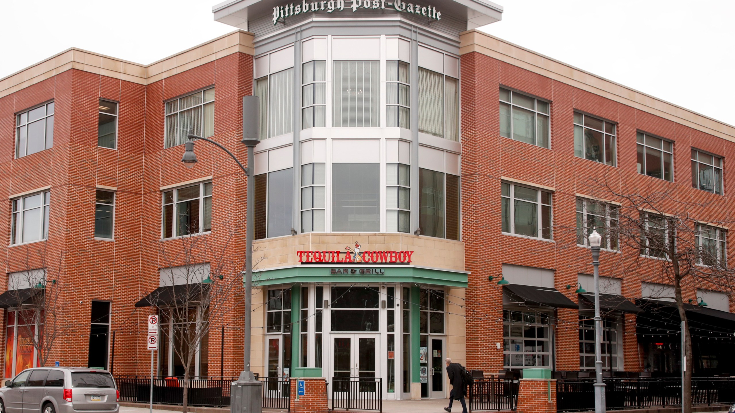 FILE - People walk past the building where the offices of the Pittsburgh Post-Gazette, Feb. 14, 2019, in Pittsburgh. (AP Photo/Keith Srakocic, File)