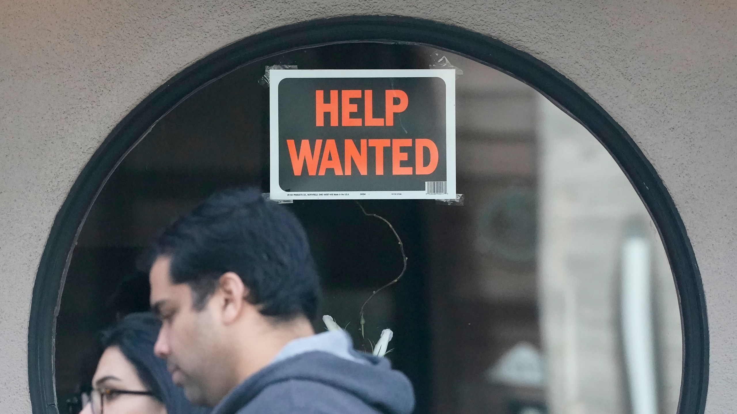 FILE - Pedestrians walk past a help wanted sign posted on the door of a restaurant in San Francisco, Tuesday, April 18, 2023. (AP Photo/Jeff Chiu, File)