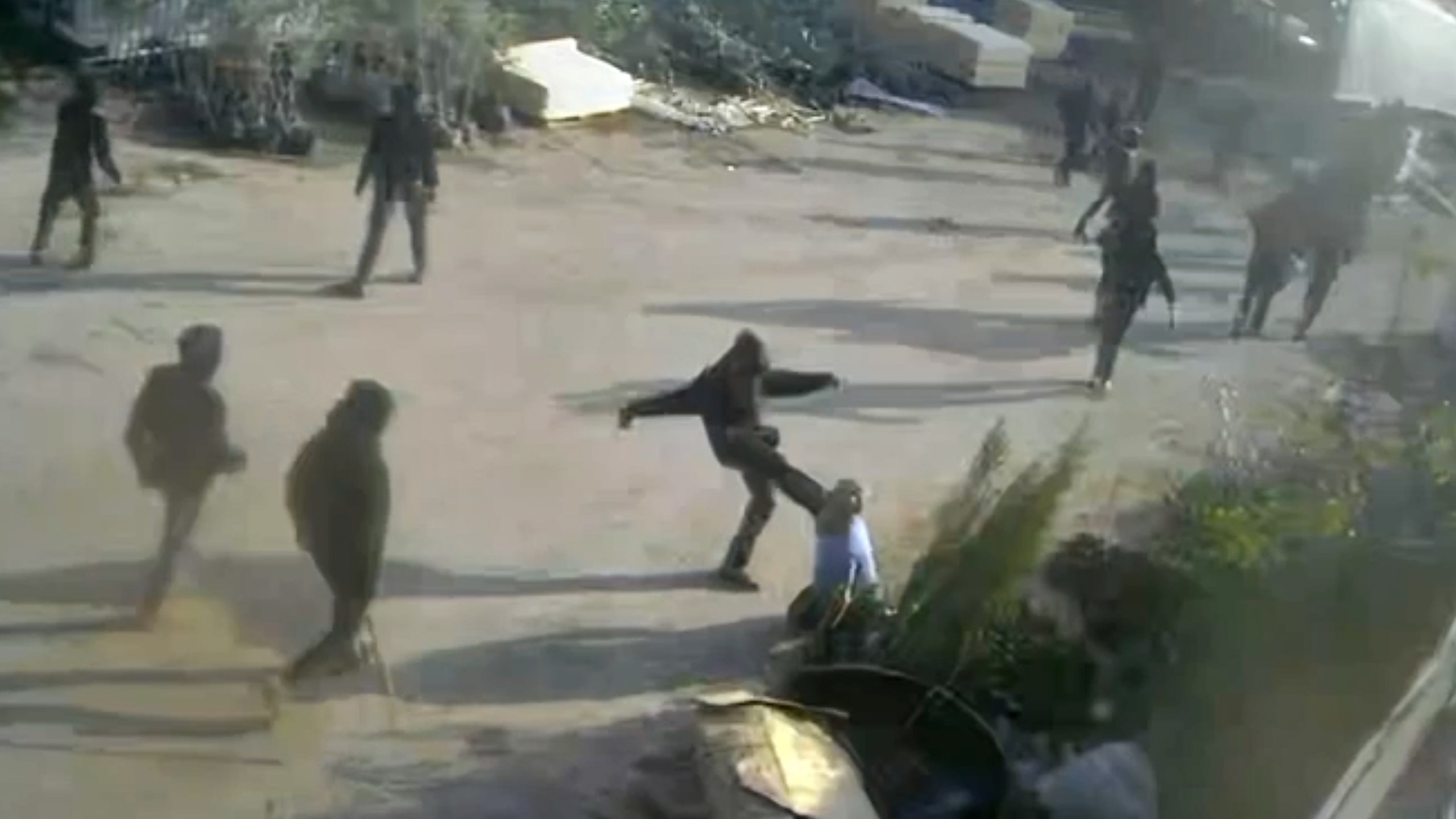 This frame grab from security camera footage filmed Jan. 8, 2026, and obtained by The Associated Press, shows men dressed mostly in black with their faces covered, one of whom is kicking a man on the ground as he tried to flee a nursery in the northern West Bank village of Deir Sharaf. Two people who witnessed the attack and are members of the family that owns the facility said the assailants were Israeli settlers beating 67-year-old Basim Saleh Yassin.(UGC via AP)