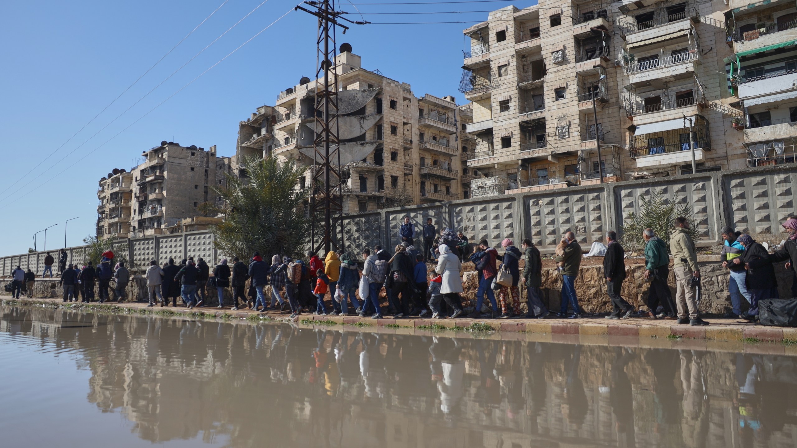 Civilians evacuate an area of the Sheikh Maqsoud neighborhood, where clashes between government forces and Kurdish fighters have been taking place in the northern city of Aleppo, Syria, Saturday, Jan. 10, 2026. (AP Photo/Omar Albam)