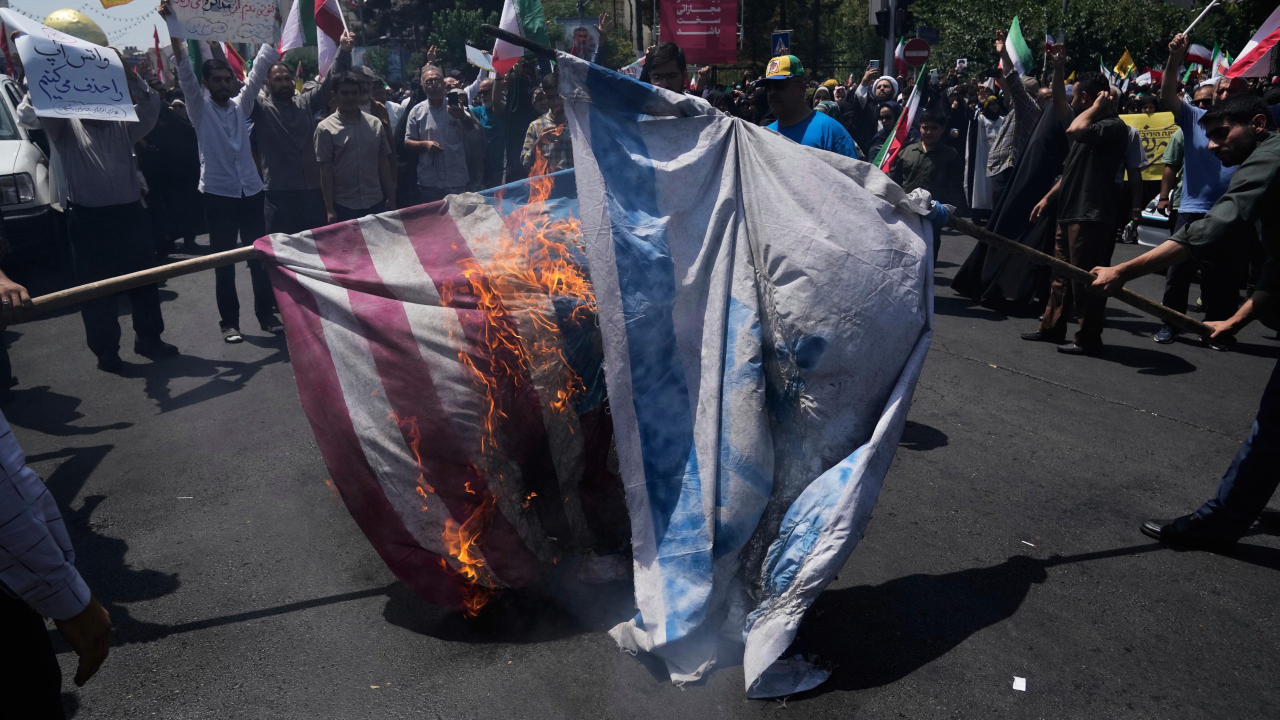 FILE - Iranian protestors burn representations of the Israeli and U.S. flags during a protest to condemn Israeli attacks on multiple cities across Iran, after the Friday prayers ceremony in Tehran, Iran, Friday, June 20, 2025. (AP Photo/Vahid Salemi), File)
