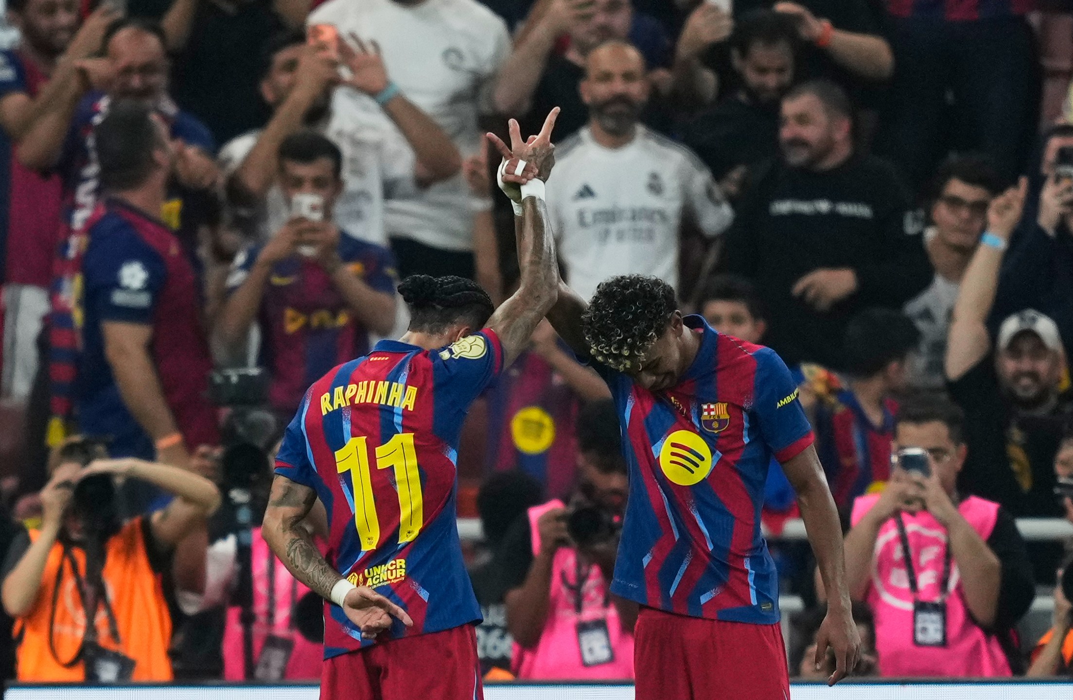 Barcelona's Raphinha, left, celebrates with teammate Lamine Yamal after scoring the opening goal during the Spanish Super Cup final soccer match against Real Madrid at King Abdullah Sports City Stadium in Jeddah, Saudi Arabia, Sunday, Jan. 11, 2026. (AP Photo/Altaf Qadri)