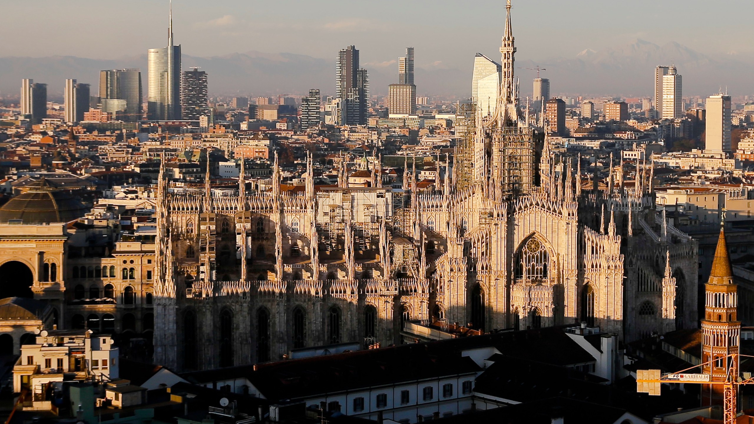FILE - The pinnacles of the Duomo cathedral are lit by the afternoon declining sun and backdropped by the new Business Center in Milan, northern Italy, Jan. 4, 2017. (AP Photo/Luca Bruno, File)