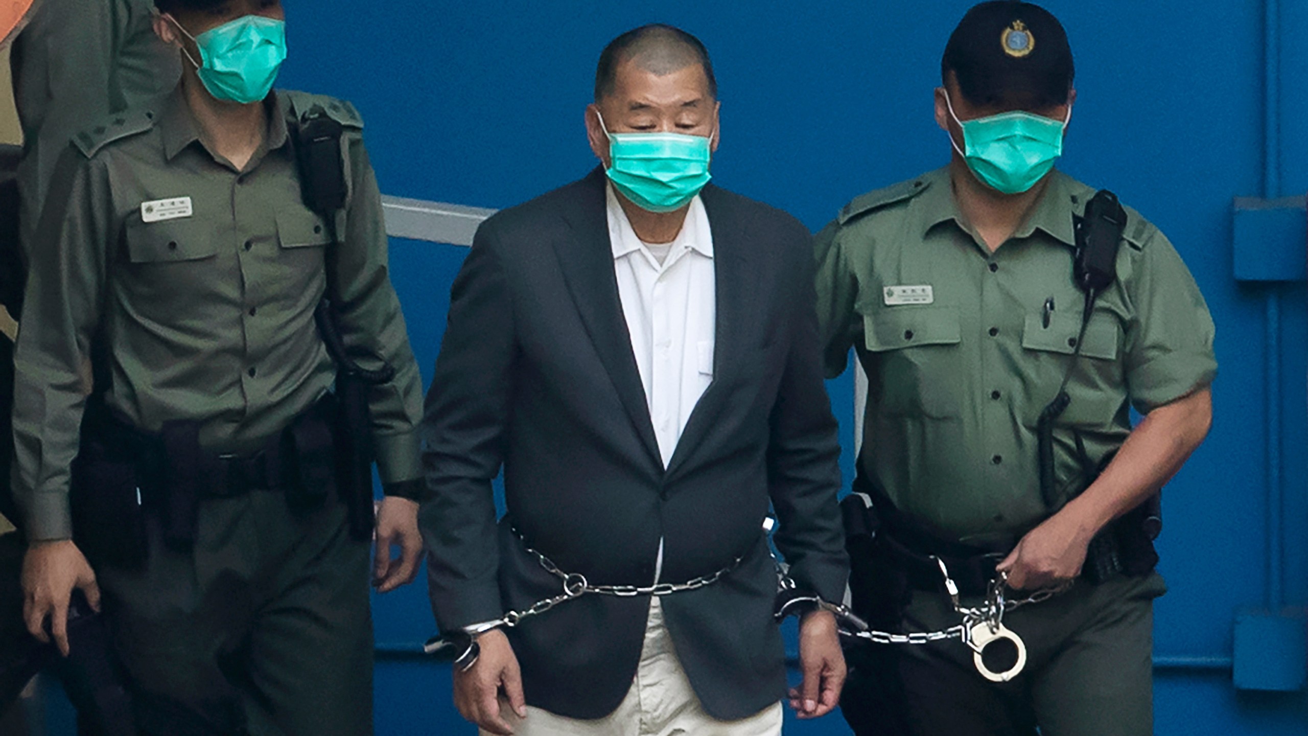 FILE- Hong Kong media tycoon Jimmy Lai is escorted by Correctional Services officers to get on a prison van before appearing in a court in Hong Kong, Dec. 12, 2020. (AP Photo/Kin Cheung, File)