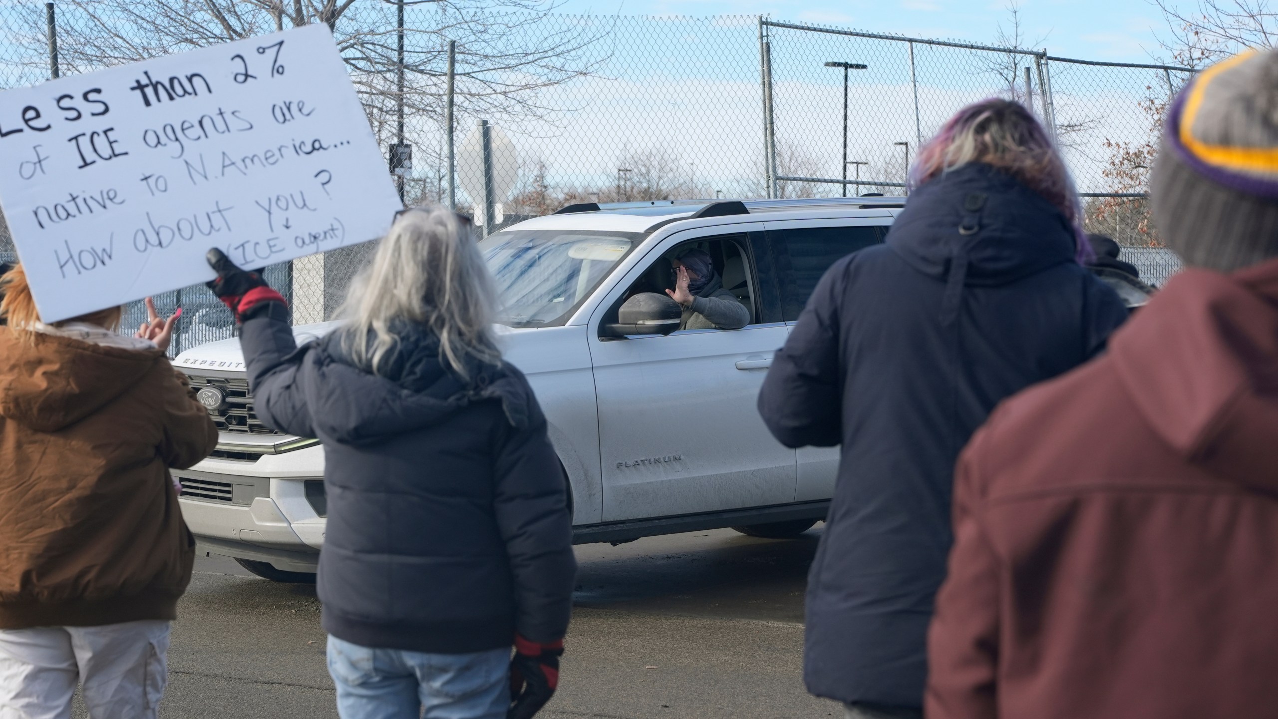 An Immigration and Customs Enforcement (ICE) agent waves at protesters while leaving the Bishop Whipple Federal Building, Monday, Jan. 12, 2026, in Minneapolis. (AP Photo/Jen Golbeck)