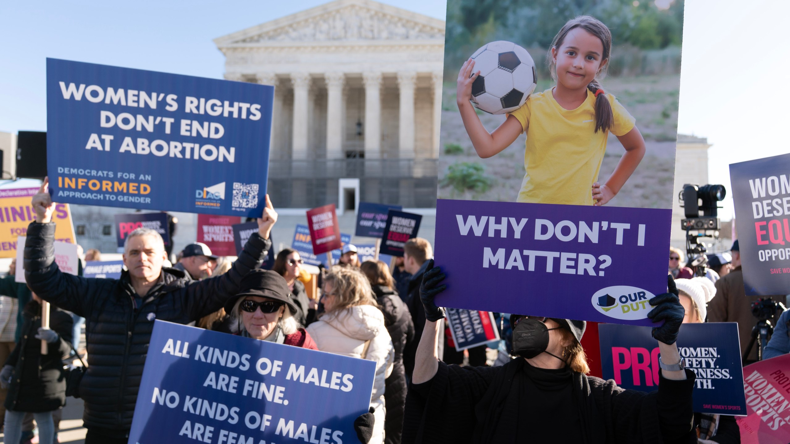 Protesters gather outside the Supreme Court as it hears arguments over state laws barring transgender girls and women from playing on school athletic teams, Tuesday, Jan. 13, 2026, in Washington. (AP Photo/Jose Luis Magana)
