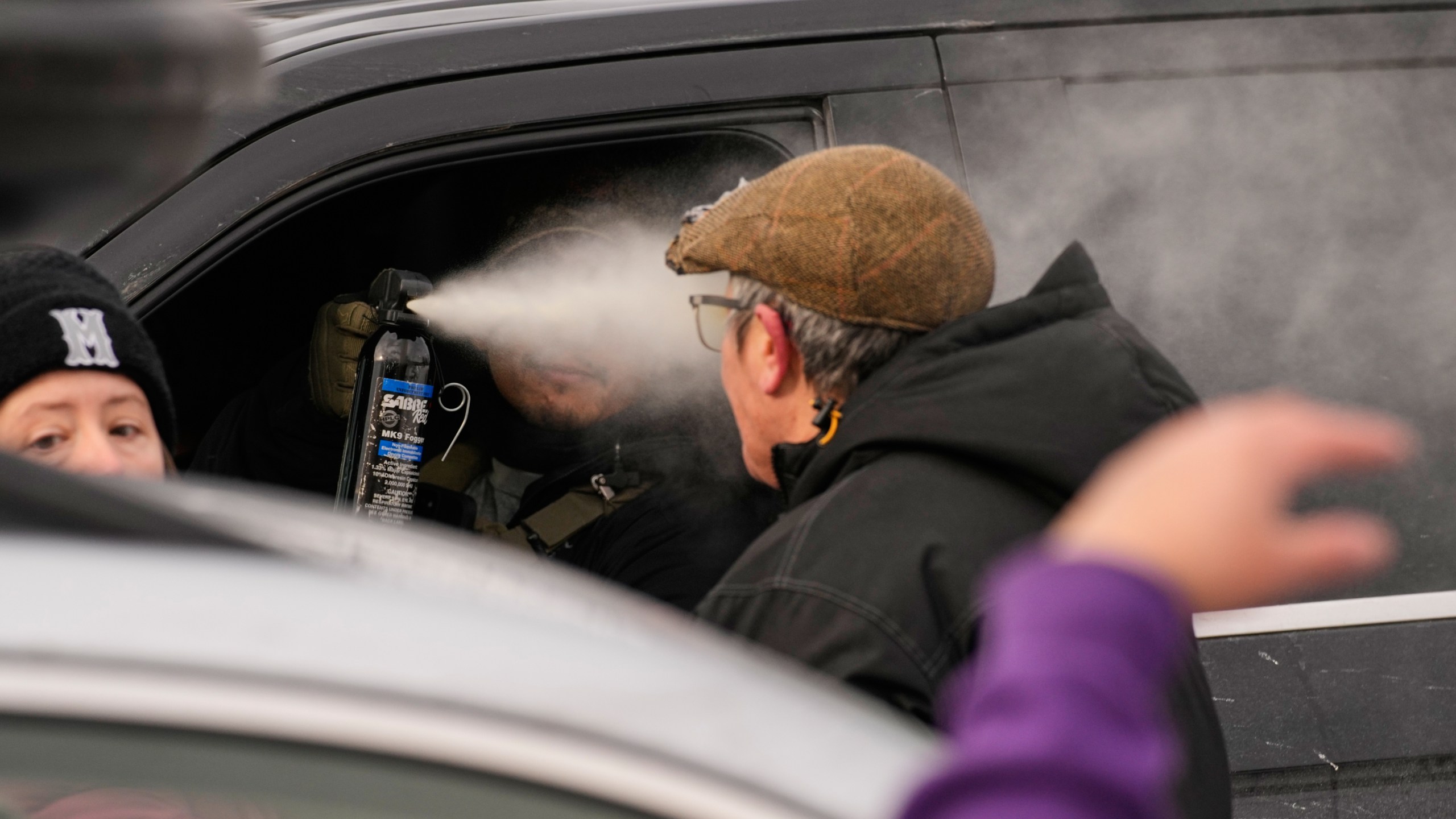 A federal immigration officer deploys pepper spray as officers make an arrest Sunday, Jan. 11, 2026, in Minneapolis. (AP Photo/John Locher)