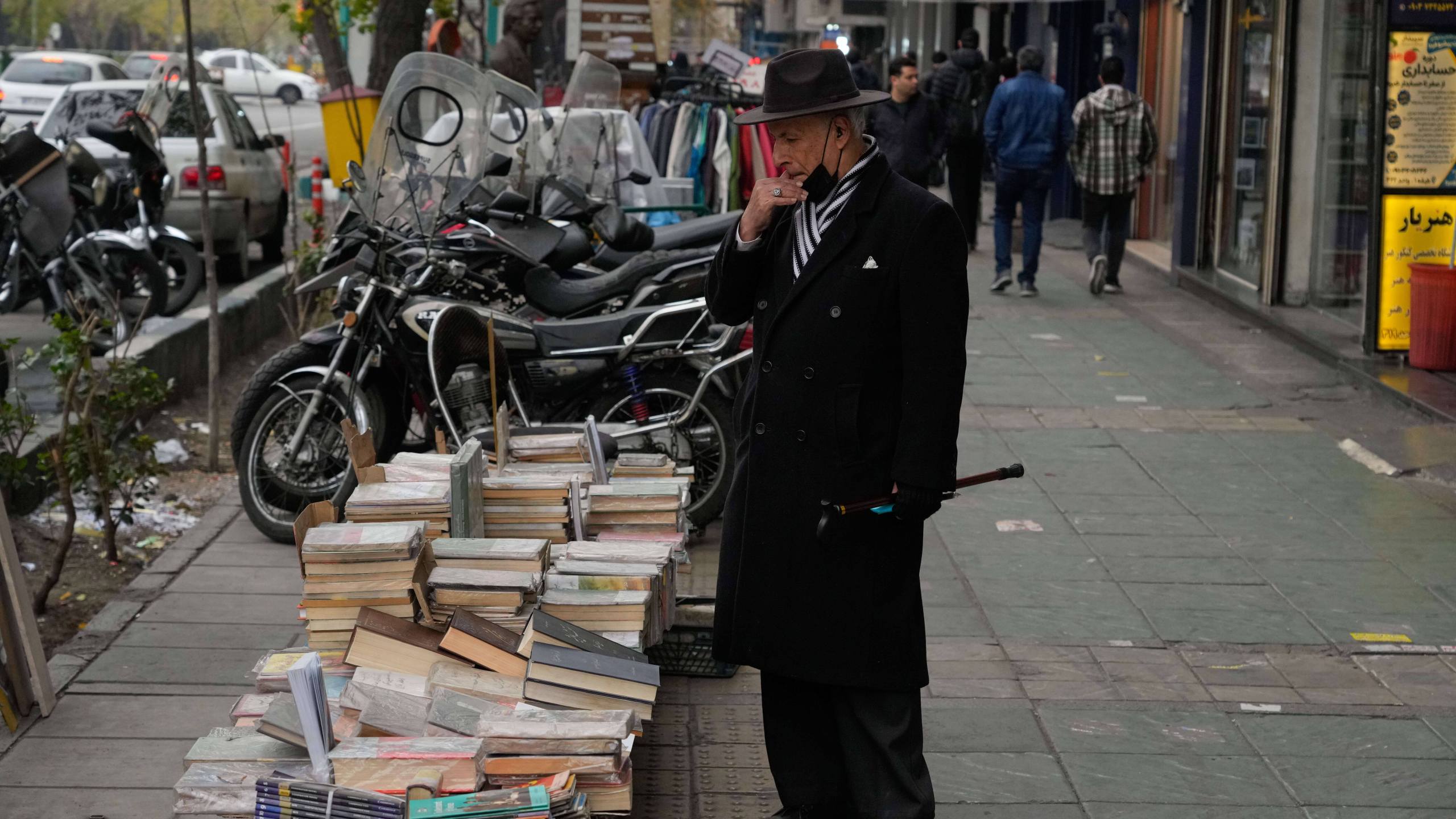 A man looks at books which are placed for sale on a sidewalk in downtown Tehran, Iran, Thursday, Jan. 15, 2026. (AP Photo/Vahid Salemi)