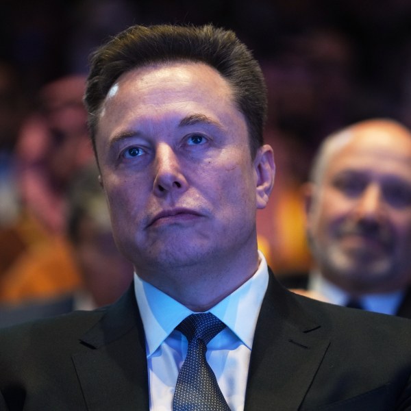 Front-facing photo of Elon Musk in a suit and tie