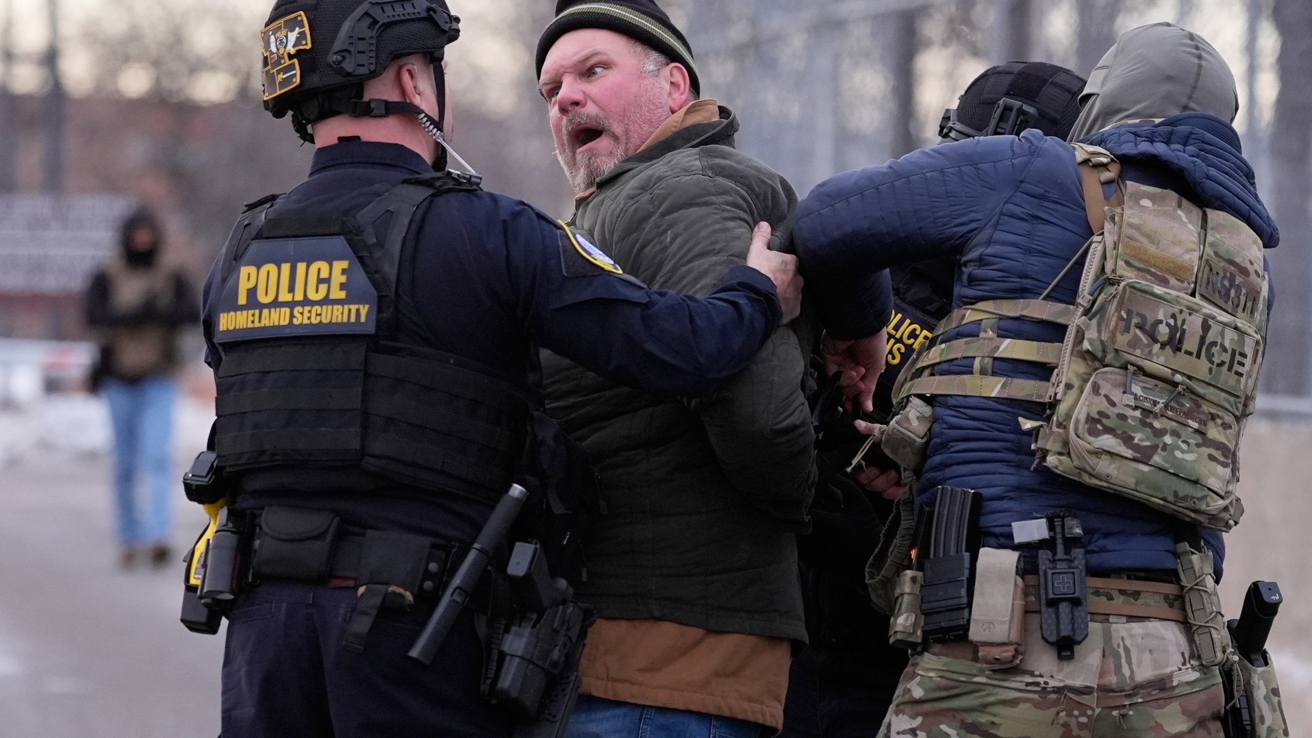 Law enforcement detain a man outside the Bishop Henry Whipple Federal Building.