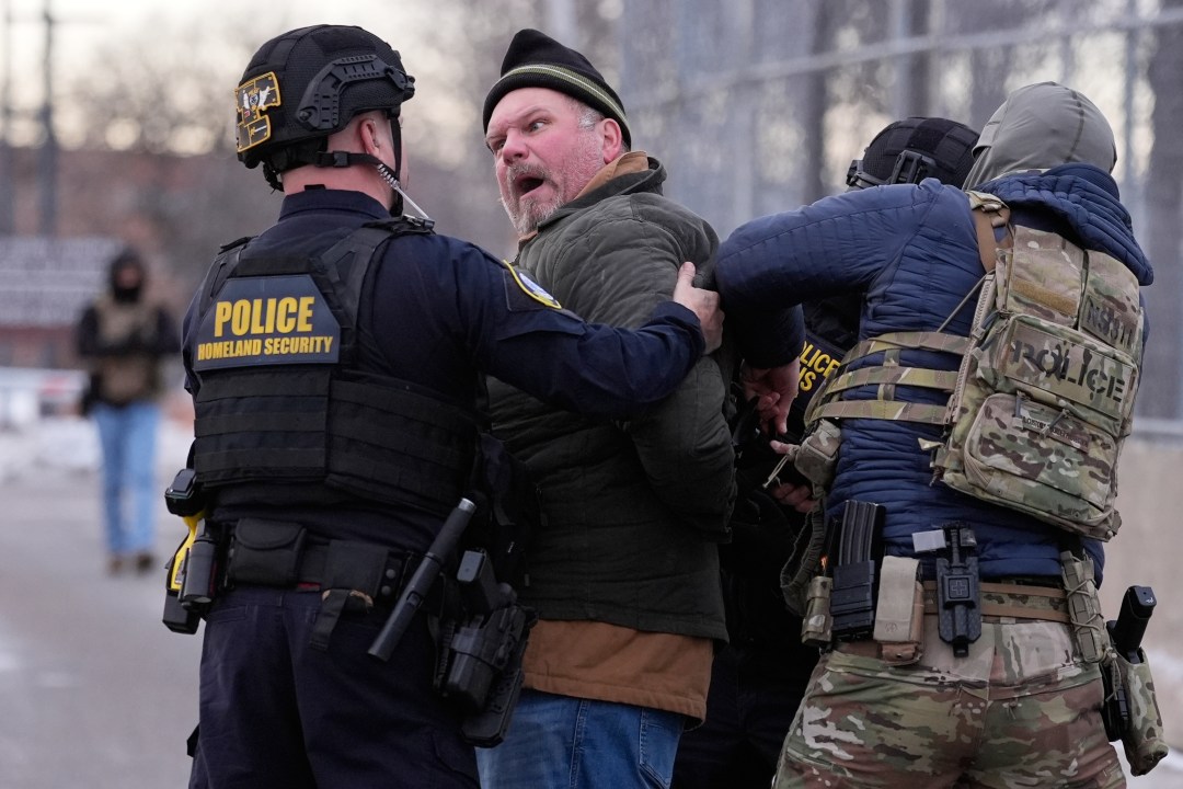 Law enforcement detain a man outside the Bishop Henry Whipple Federal Building.