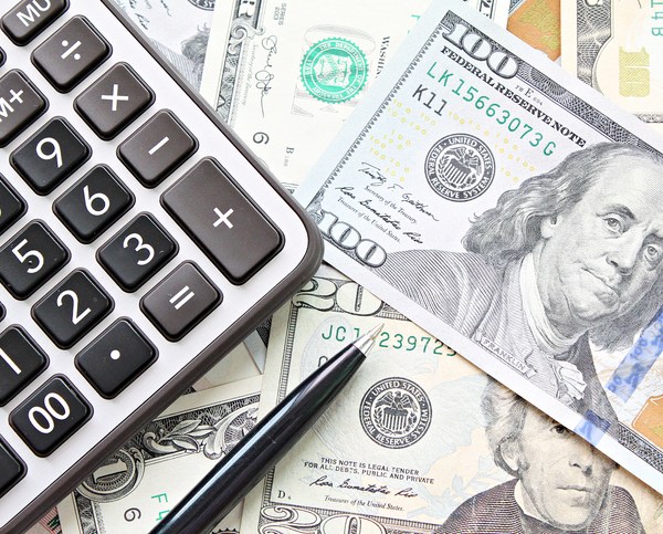 A calculator, pen and money scattered on a table