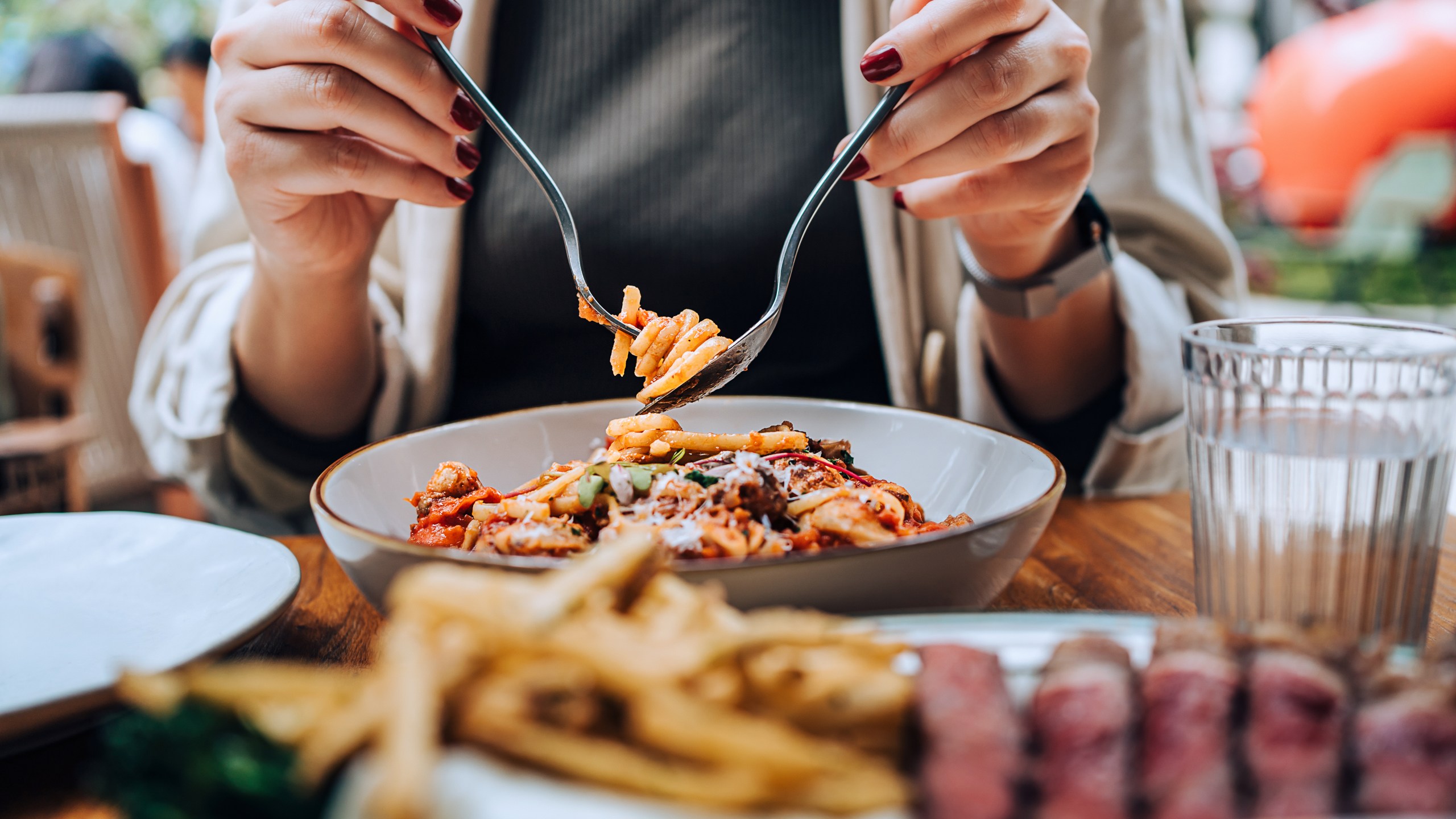 A woman sitting at a dining table holding cutleries