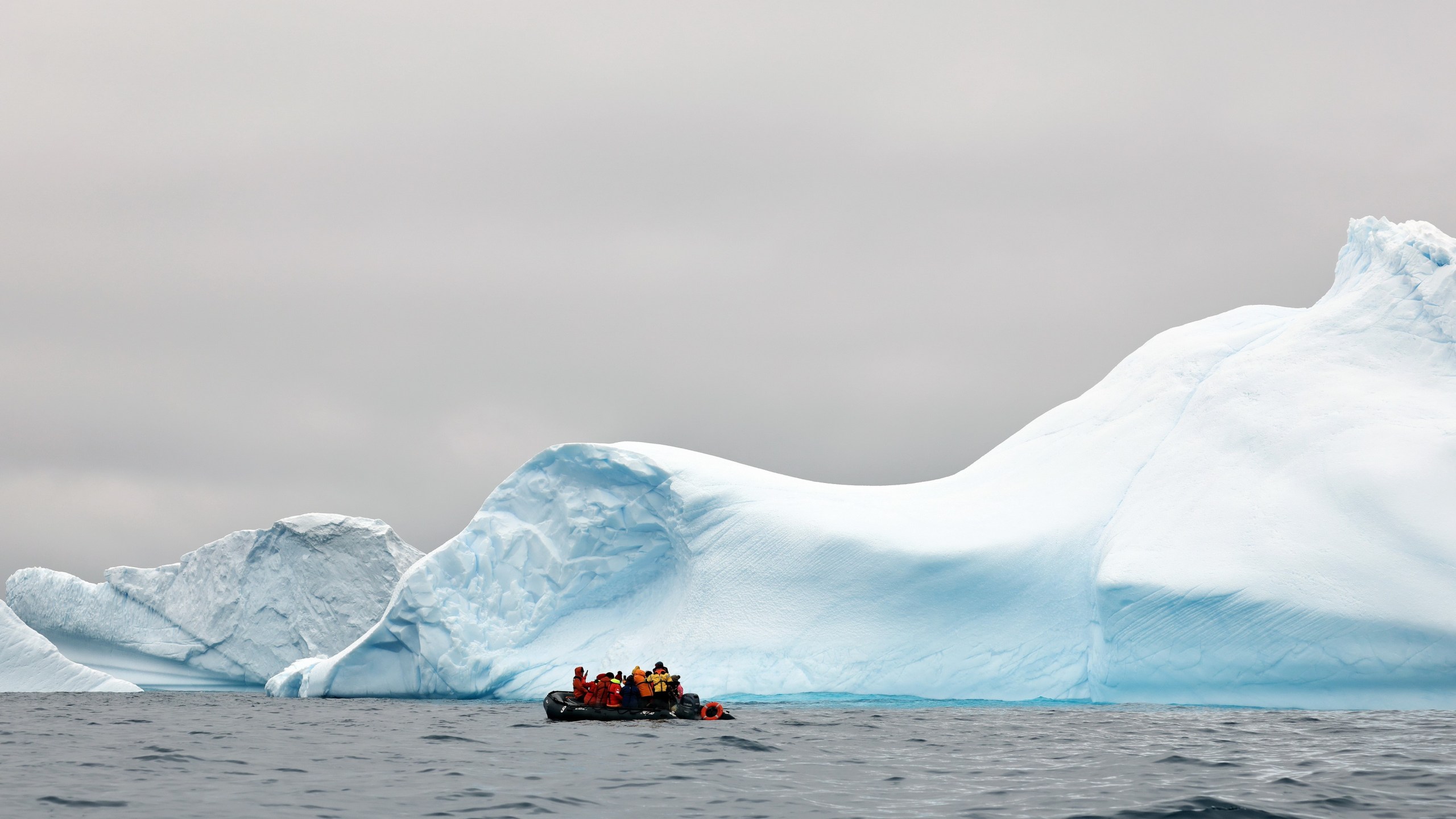 People take photos of an iceberg near the coast of Spert Island