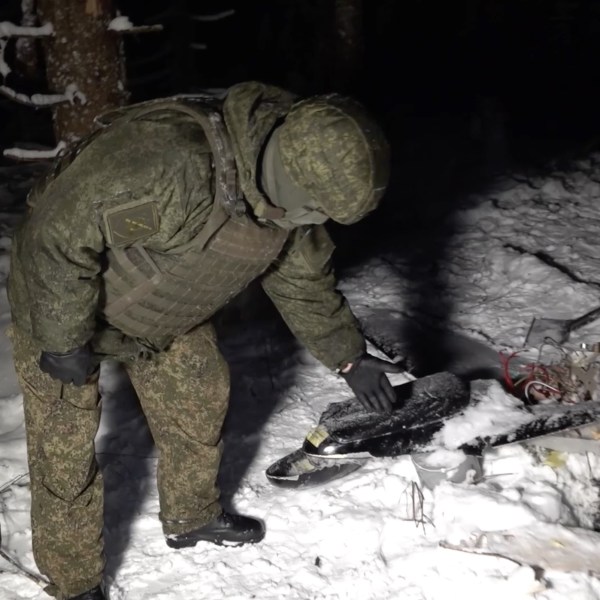 Russian soldier standing over drone wreckage in snow