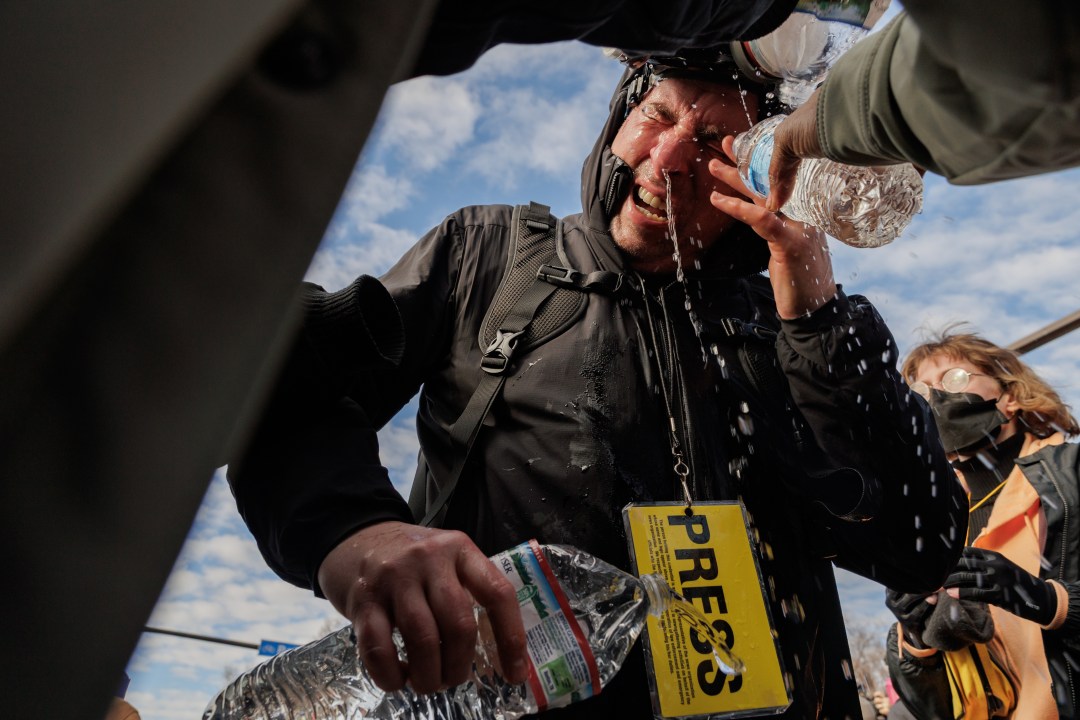 A member of the Press rinses his eyes with water after tear gas exposure