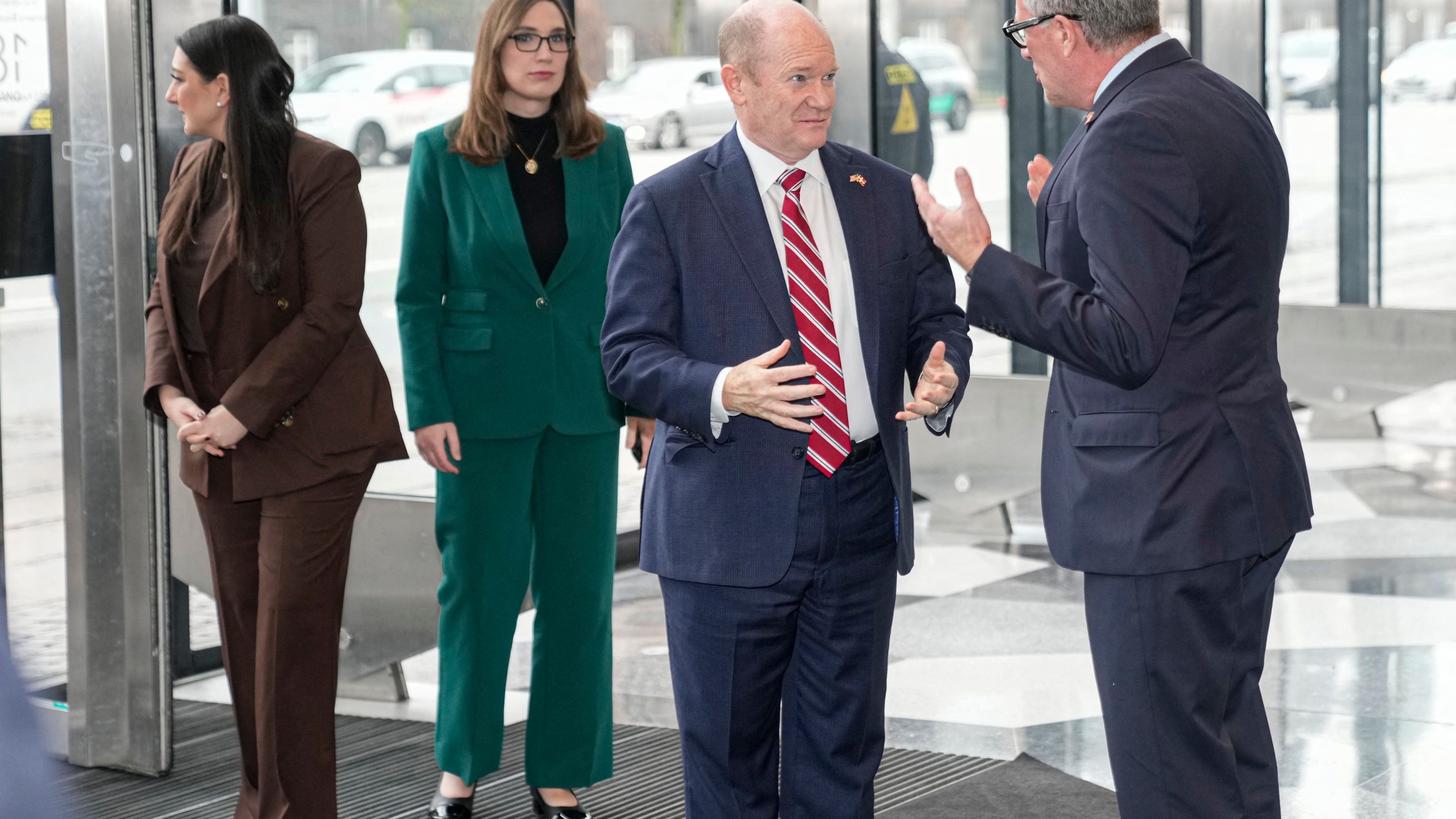 Rep. Sara Jacobs, Rep. Sarah McBride and Senator Chris Coons and Danish Industry’s CEO Lars Sandahl Sorensen gather in the lobby of a building during a visit in Denmark