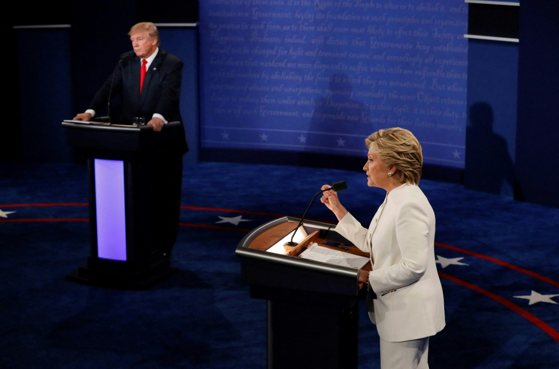 Hillary Clinton speaks at a podium as Republican presidential nominee Donald Trump looks on during a debate 